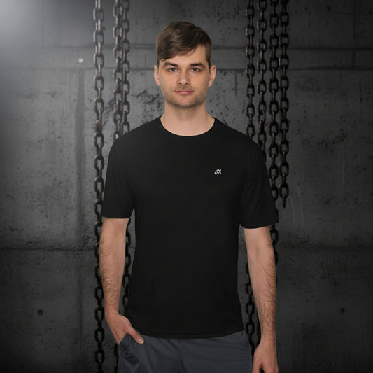 Modelo fitness posando frontalmente con la camiseta Core Gravity Tech-Shell. Fondo de columna de hormigón bruto oscuro y cadenas de gimnasio industriales desenfocadas. Iluminación cenital fría