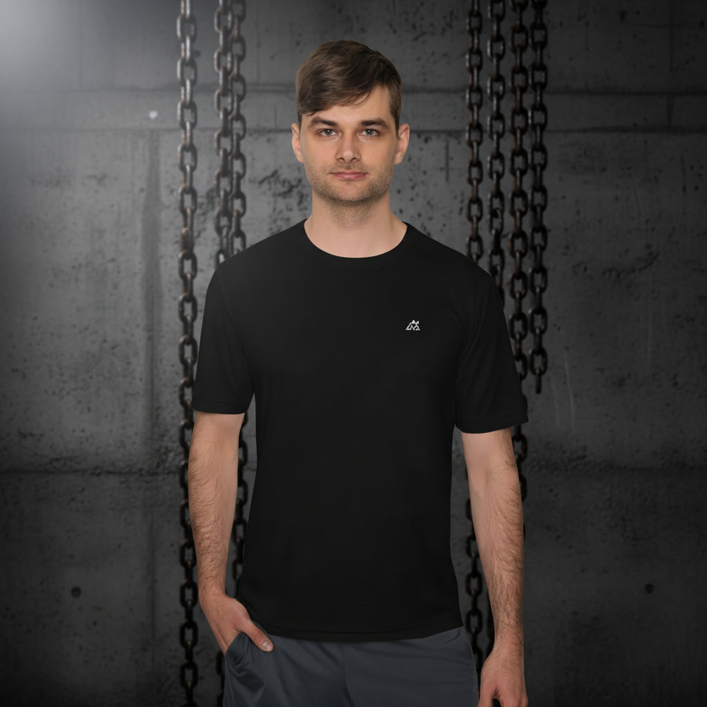 Modelo fitness posando frontalmente con la camiseta Core Gravity Tech-Shell. Fondo de columna de hormigón bruto oscuro y cadenas de gimnasio industriales desenfocadas. Iluminación cenital fría
