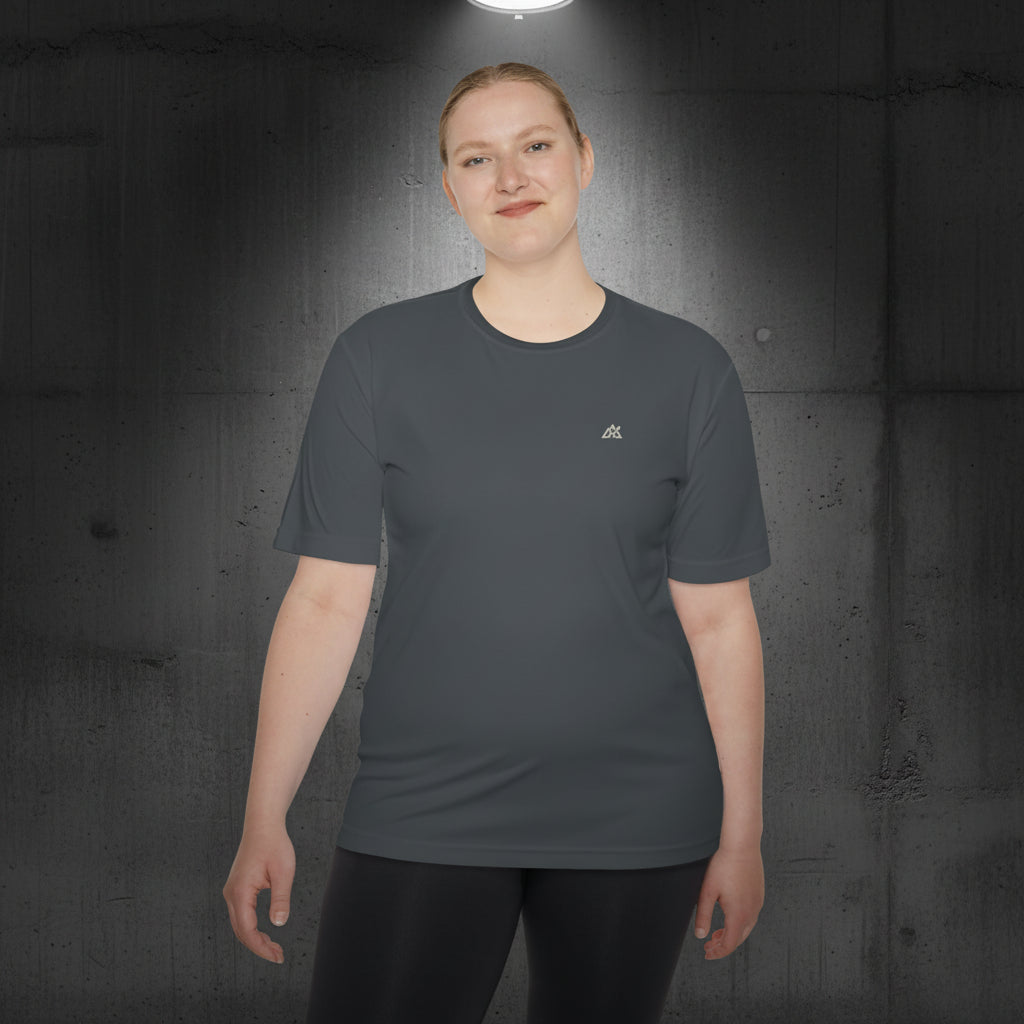 Modelo fitness posando frontalmente con la camiseta Core Gravity Tech-Shell. Fondo de columna de hormigón bruto oscuro y cadenas de gimnasio industriales desenfocadas. Iluminación cenital fría